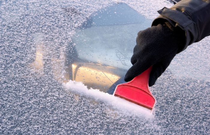 Une Femme Nettoie La Vitre Avec Un Grattoir Pendant Les Gelées